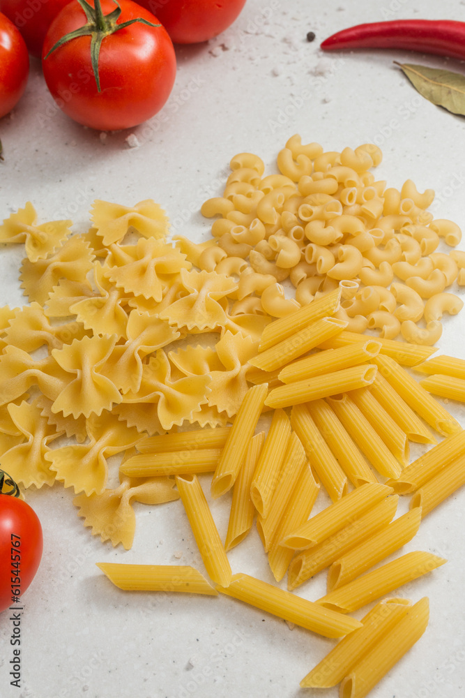 Italian pasta on table with tomatoes, pepper and different species