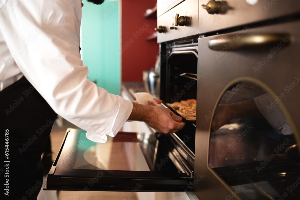 close-up shot. chef's hands put a baking sheet with chicken fillet for making sandwiches in the oven