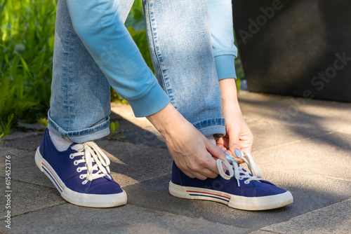 woman tying shoelaces on sneakers sitting on a bench