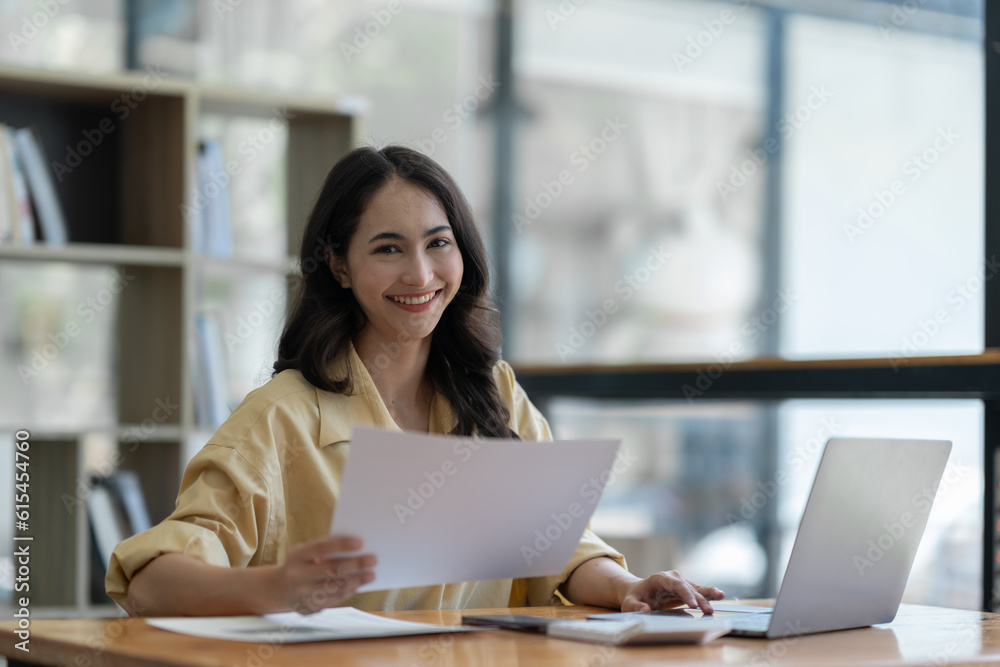 Confident Asian businesswoman using laptop calculator Paperwork for financial work, calculations on the desk, tax, report, accounting, statistics. Analytical research concept. Confident Asian businesswoman using laptop calculator Paperwork for financial work, calculations on the desk, tax, report, accounting, statistics. Analytical research concept.