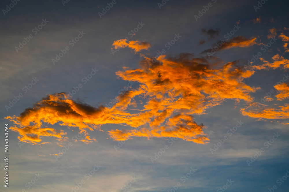Colorful fantasy sunset clouds sky.Vibrant sunset sky. Warm fire tones. Blue, orange and yellow sunset sky.