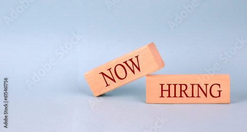 NOW HIRING text on the wooden block, blue background