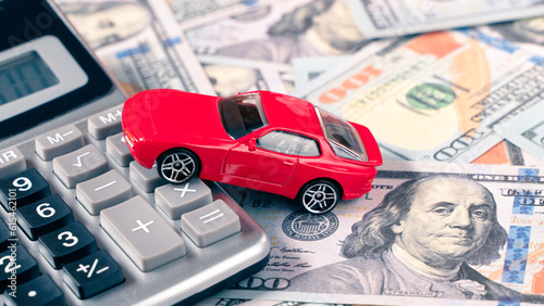 Red car on calculator on US dollar banknotes. Car financial or insurance concept. 