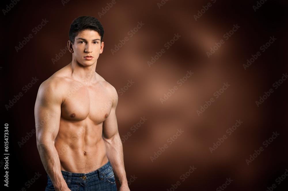 Fototapeta premium Muscular sporty young guy posing on background.