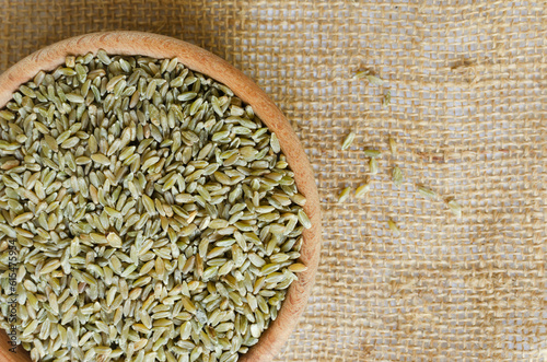 Raw freekeh or firik in a wooden bowl on burlap. Concept of healthy eating. Rustic style. Horizontal orientation. Top view. Copy space photo