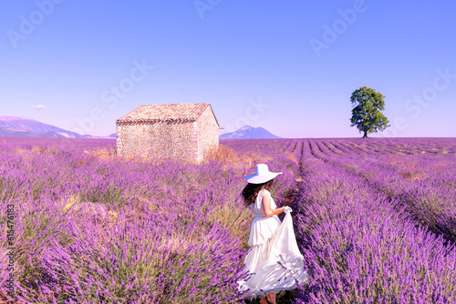 Une mariée habillée en blanc avec un chapeau dans un paysage magnifique, au milieu d'un champ de lavande dans le Luberon, pendant un voyage pendant les vacances en été dans le Sud de la France