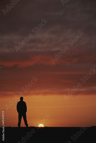 Man stands silhouetted by the sunset he's watching, Ivvavik National Park, Yukon Territory, Canada; Yukon, Canada photo