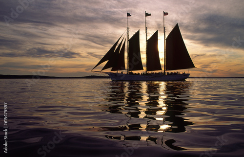 Three masted schooner under sail at sunset; Maine, United States of America