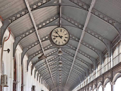 Clock hanging from the rafters of a ceiling; Maputo, Mozambique