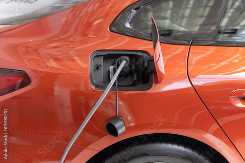 Orange electro car on charging at the station