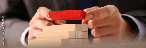 Bild auf Leinwand Businessman hand builds ladder from wooden blocks on top of red color