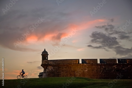 Silhouette of a cyclist and San Felipe del Morro Castle at sunset; San Juan, Puerto Rico photo