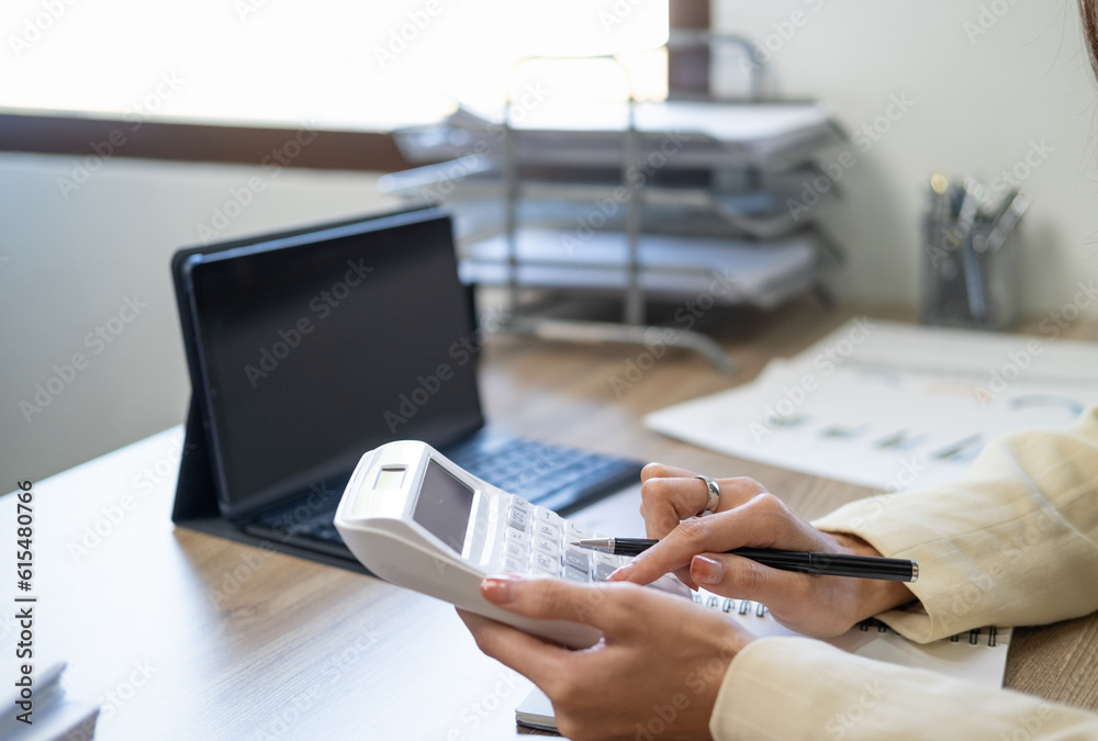 Fototapeta premium Asian female accountant or banker making calculations. Savings, finances and economy concept through a laptop.