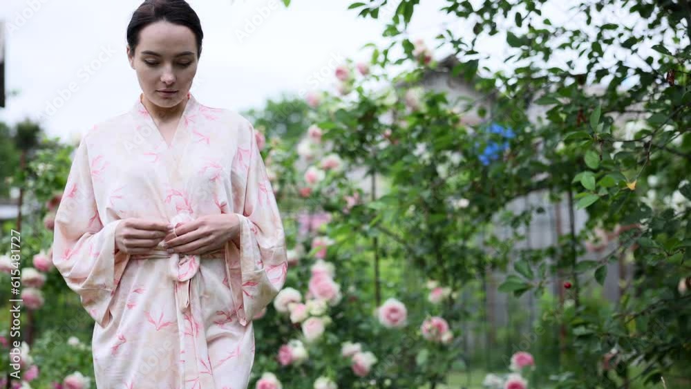 Young woman in walking in garden among blooming pink rose . Young woman in walking in garden among blooming pink rose .