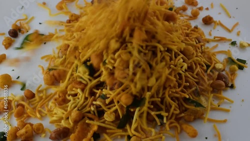 Mixture, a savory snack of India being put in a white ceramic plate