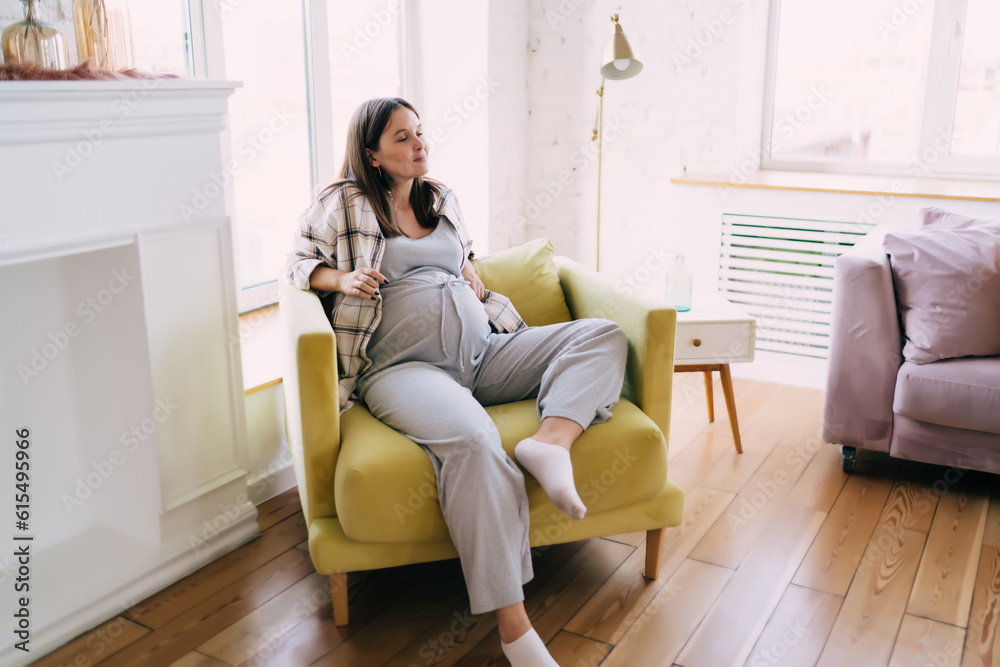 Pregnant woman resting in armchair in living room Pregnant woman resting in armchair in living room