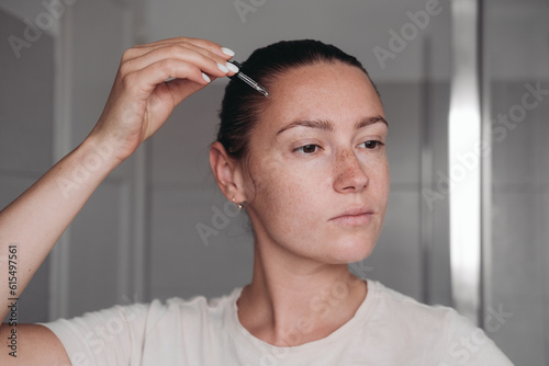 Woman applying a transparent serum on her face
