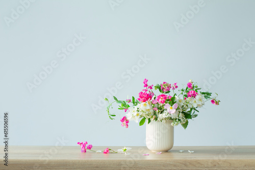 summer flowers in ceramic cup on light background