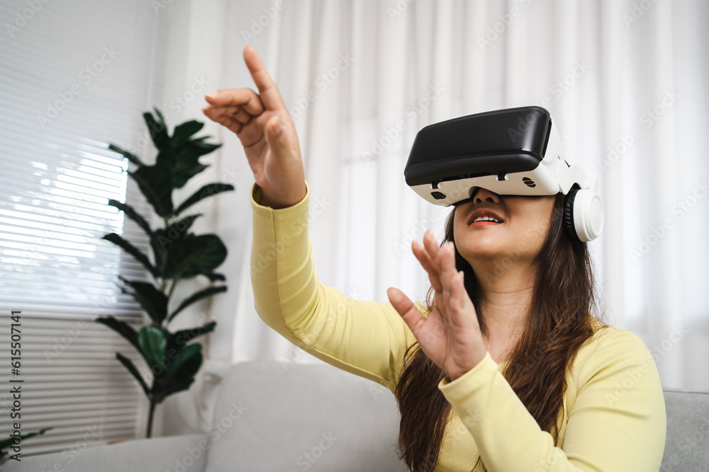 Young Asian woman gamer wearing virtual reality touching air during the VR experience Future home technology player hobby playful enjoyment concept. Young Asian woman gamer wearing virtual reality touching air during the VR experience Future home technology player hobby playful enjoyment concept.