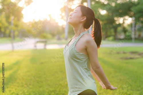 Female jogger. Fit young Asian woman with green sportswear breathing fresh air in park before running and enjoying a healthy outdoor. Fitness runner girl in public park. Wellness being concept