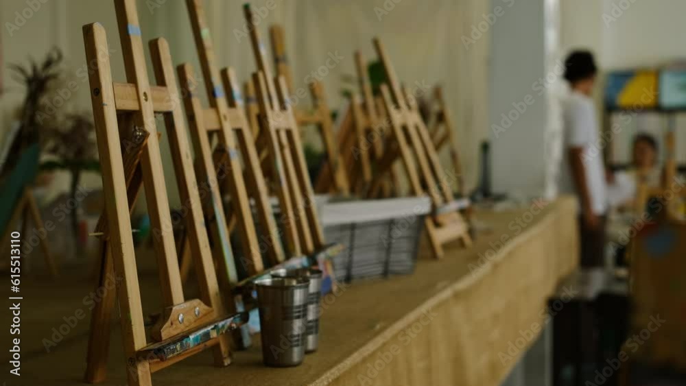Interior of the creative art workshop with wooden easels and paint brushes. Shot in slow motion Interior of the creative art workshop with wooden easels and paint brushes. Shot in slow motion