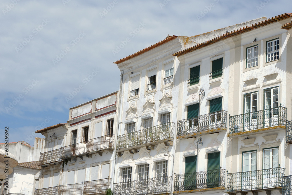 Old historical buildings with shabby facades of white and beige colours downtown Evora, Portugal. Conceptual for protection, restoration and renovation