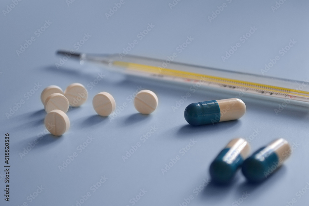 background for a medical website or article, pills, capsules and mercury thermometer on a blue background, medicines, medical care background for a medical website or article, pills, capsules and mercury thermometer on a blue background, medicines, medical care