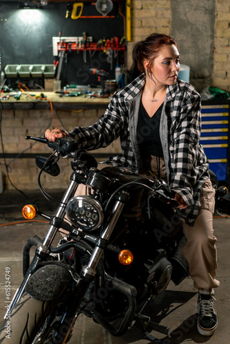 Creative authentic motorcycle workshop garage beautiful young girl biker sitting on a cool motorcycle