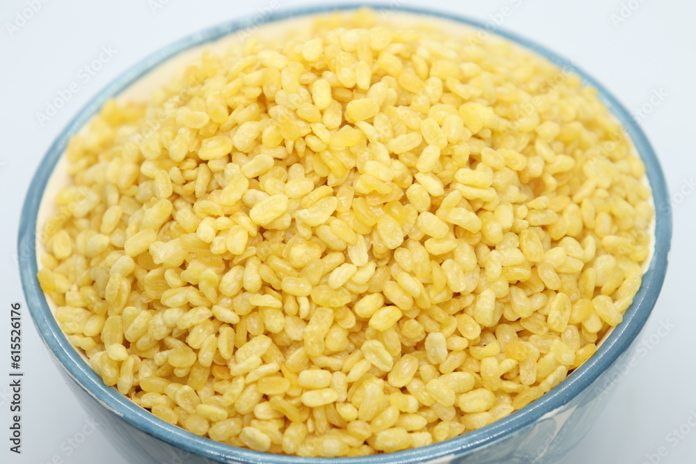 Moong Dal Namkeeen, Indian Namkeen Snack Food, Moong dal isolated served in a blue bowl in top view, white background. Mixture, Yellow split salty mung dal or moong dal namkeen. Top close up. Moong Dal Namkeeen, Indian Namkeen Snack Food, Moong dal isolated served in a blue bowl in top view, white background. Mixture, Yellow split salty mung dal or moong dal namkeen. Top close up.