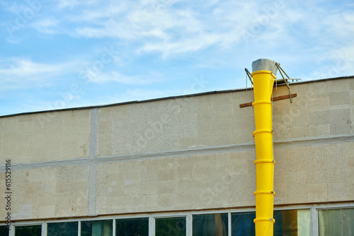 Debris chute, removing debris and waste from roof of the building. Plastic garbage chute against blue sky. Garbage chute, tube for removing waste, eliminate debris. Dispose rubbish from.roof
