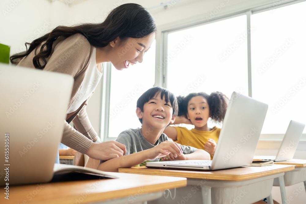 Asian Female teacher helping school kids using laptop Asian Female teacher helping school kids using laptop