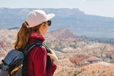 Woman with a backpack looking on the panorama of Bryce canyon in Utah.