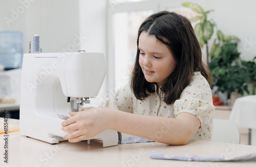 Little girl working with modern sewing machine on seamstress master class