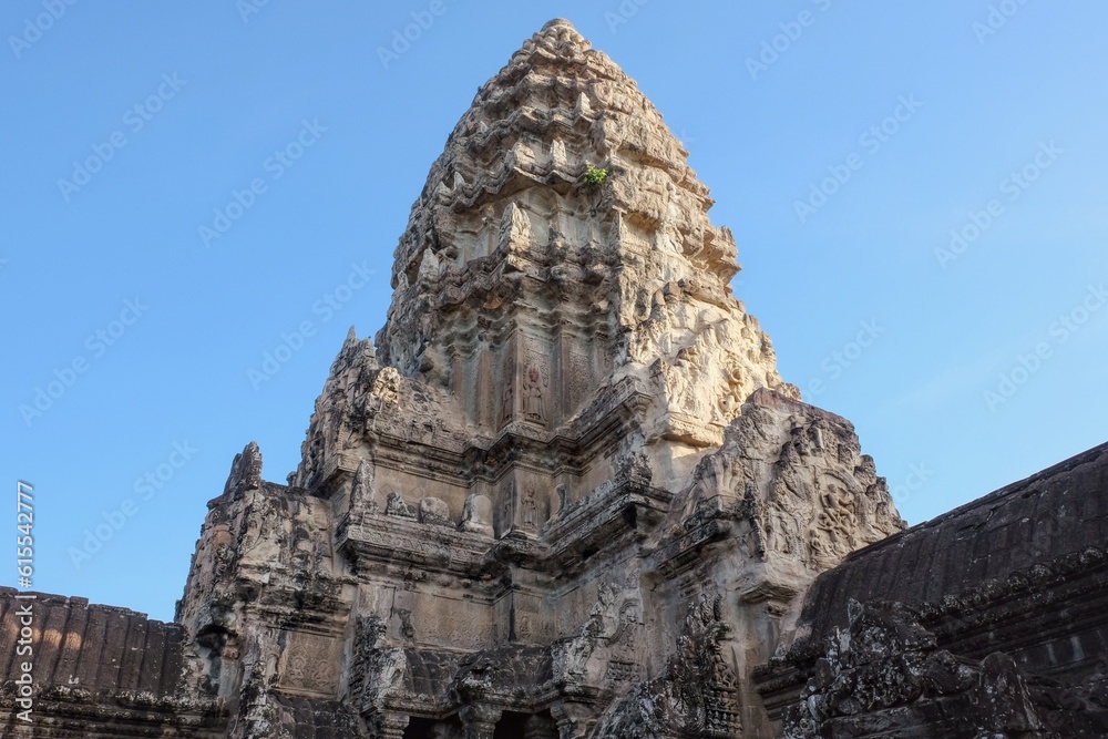 Angkor Wat stone tower under vibrant blue sky.