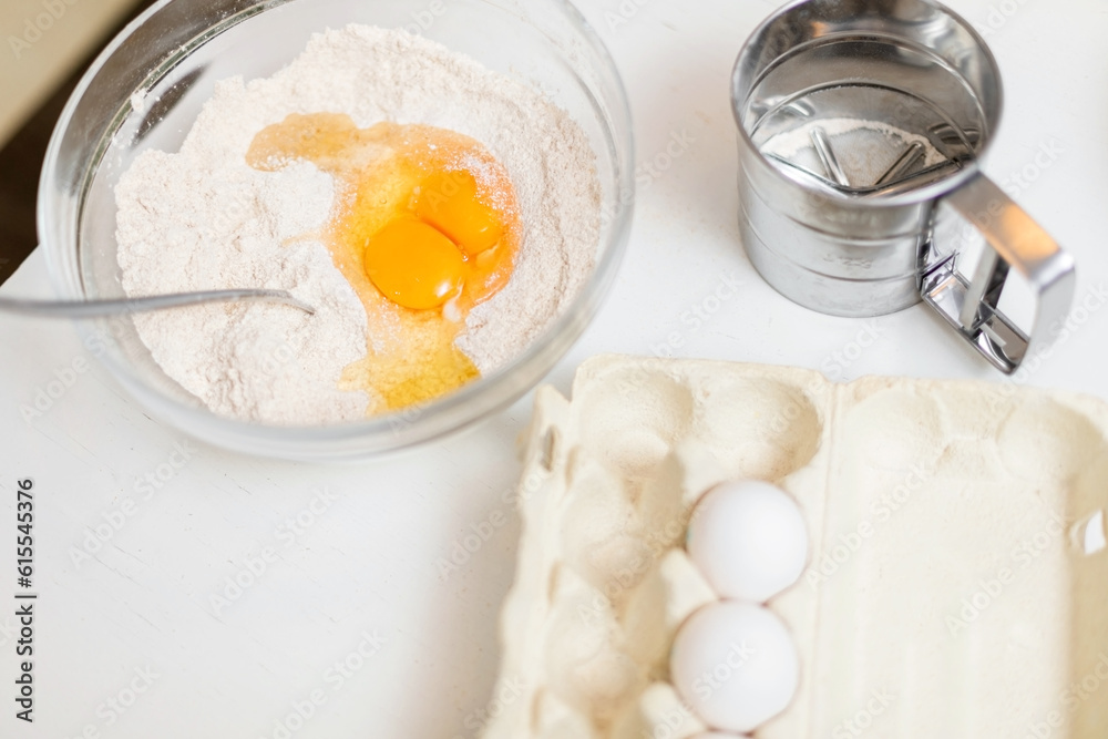 Cracked chicken eggs in a bowl of flour on a white homemade table. Homemade baking concept. Step by step . Top view Cracked chicken eggs in a bowl of flour on a white homemade table. Homemade baking concept. Step by step . Top view