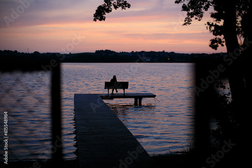 Summer on Kashubia: Silhouette of a boy at the lake pier