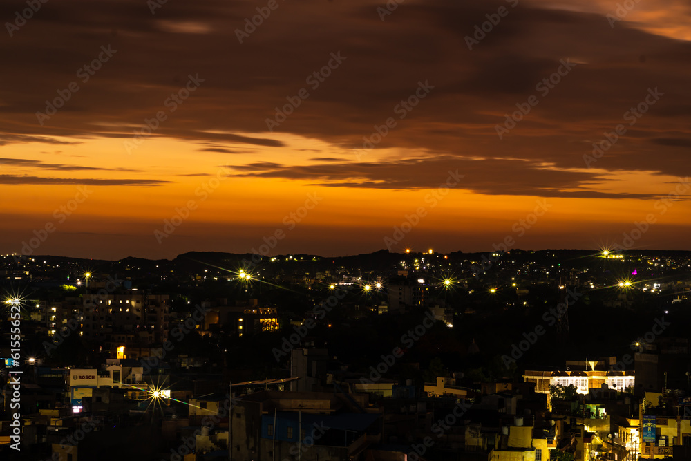 city night light view with dramatic sunset orange sky from mountain top at evening
