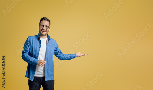 Quadro su tela Portrait of happy salesman showing something on palm while standing against yell