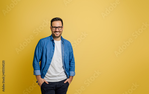 Fototapeta Portrait of smiling confident male entrepreneur with hands in pockets posing on