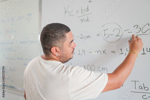 professor Brasileiro explicando um problema de matemática na lousa durante aula em um curso para adultos no Brasil