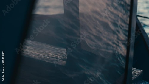 Waves reflecting on glass screen of a motorboat. Sea cruise voyage in blue ocean. Texture of water on surface of sea at sunset. Fast boat vessel swimming on wave of stormy sea. Window of sailing yacht photo