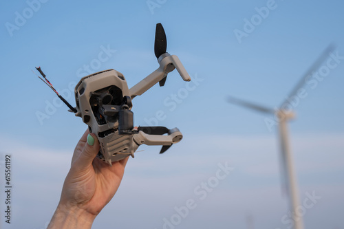 Fotografie Woman holding a crashed drone against the backdrop of windmills.