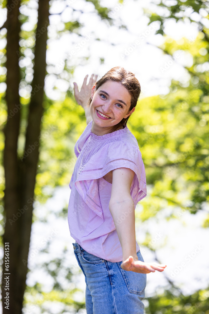 Young woman with her arms wide spread is enjoying in the sunny summer day in the forest between the trees, side view. High quality photo Young woman with her arms wide spread is enjoying in the sunny summer day in the forest between the trees, side view. High quality photo