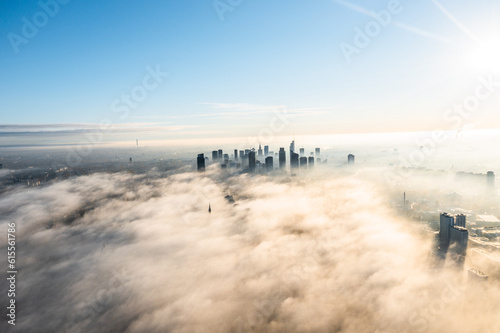 Drone flies towards the urban landscape with buildings in the fog at sunrise. Aerial view of cityscape in the fog at sunrise. Warsaw Poland.