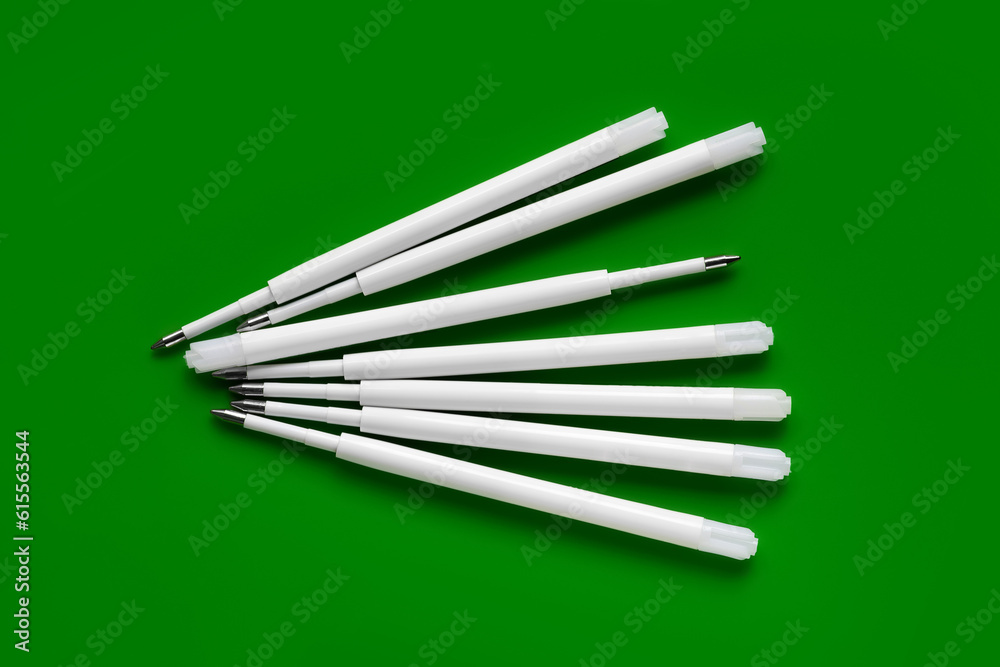 Plastic rods for a ballpoint pen. Ballpoint pen refills. White ink refills on a green Plastic rods for a ballpoint pen. Ballpoint pen refills. White ink refills on a green