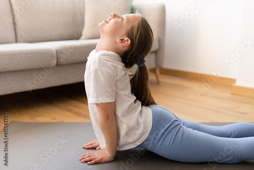 Glad cute millennial caucasian teenager girl in sportswear doing stretching workout, practicing yoga