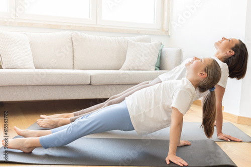 Cheerful millennial caucasian mother in sportswear and teenage daughter practice yoga, doing handstand