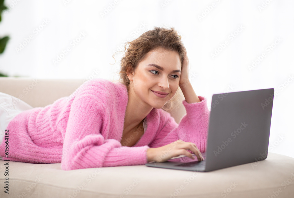Smiling Woman Surfing Internet On Laptop While Relaxing On Couch At Home Smiling Woman Surfing Internet On Laptop While Relaxing On Couch At Home