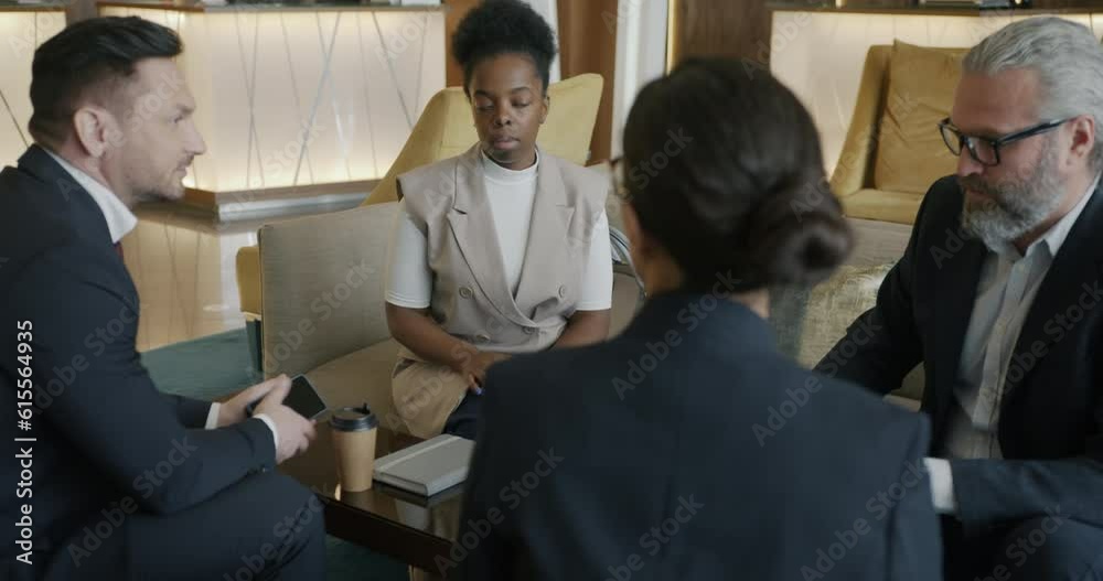 Diverse group of businesspeople men and women are discussing project during talks in hotel lobby. Communication and cooperation concept. Diverse group of businesspeople men and women are discussing project during talks in hotel lobby. Communication and cooperation concept.