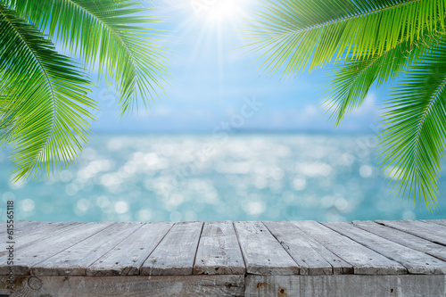 Empty wood table with seascape and palm leaves, blur bokeh light